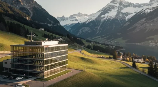 Bürogebäude in bergiger Landschaft mit moderner Architektur und Schweizer Alpen im Hintergrund